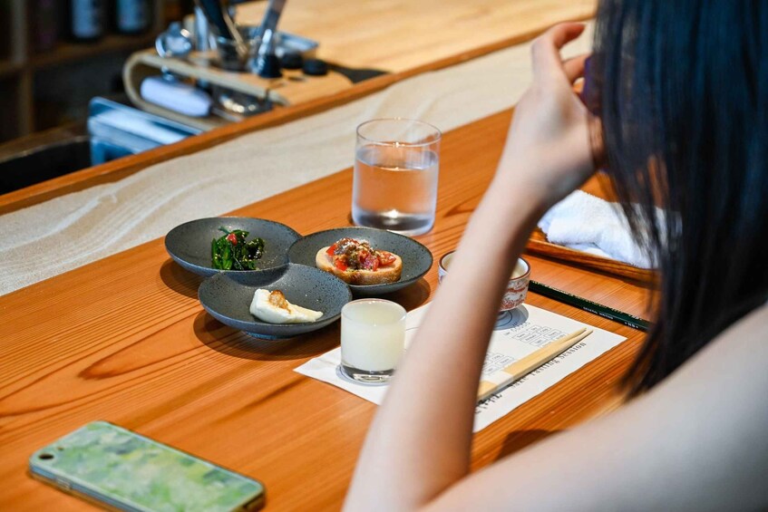 A wooden table with plates of food, a glass of water, and a smartphone. 5