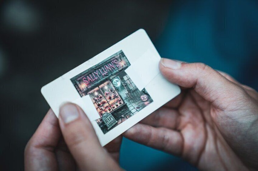 A hand holding a card with a building illustration. 2
