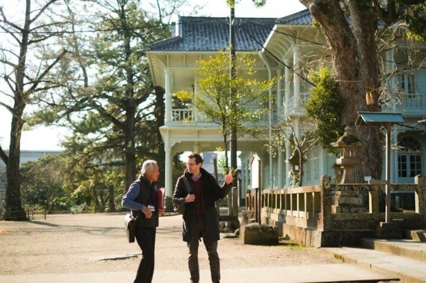 Two people walking on a path with a gazebo and trees in the background. 3