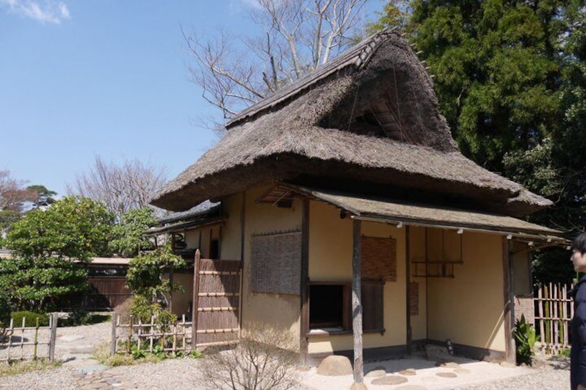 A traditional Japanese house with a thatched roof, wooden walls, and a small garden. 4