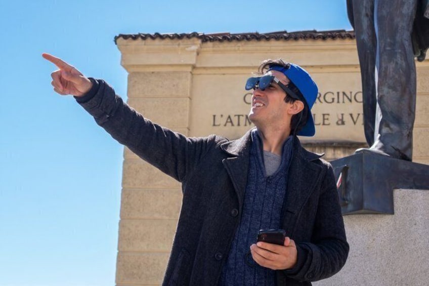 Una persona indica un edificio con colonne e una statua sullo sfondo. 5