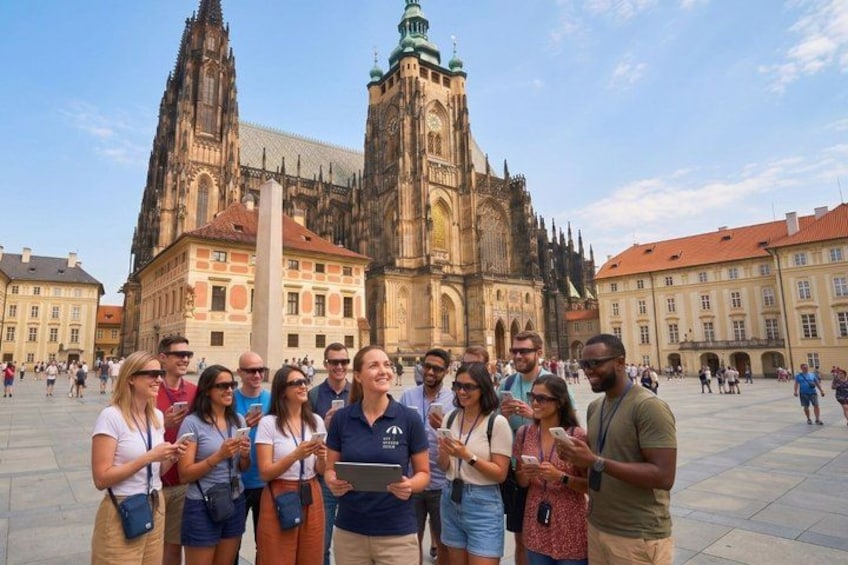 A group of tourists in front of a historic cathedral with twin spires and a tall clock tower. 1
