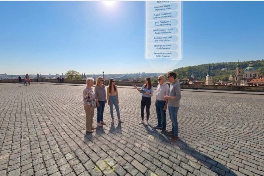 Un gruppo di persone in piedi su una superficie pavimentata, con vista chiara su un castello e sullo skyline urbano sullo sfondo. 3