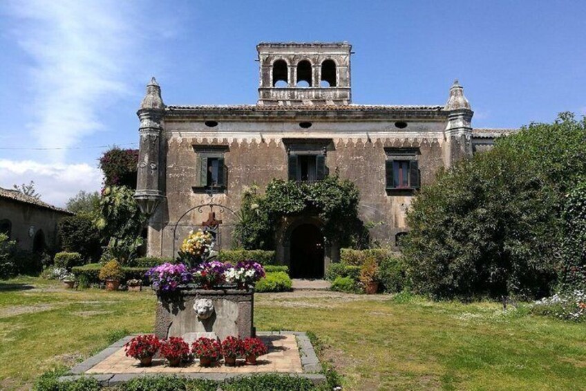 A historic building with a bell tower, surrounded by well-maintained gardens and a clear sky. 5