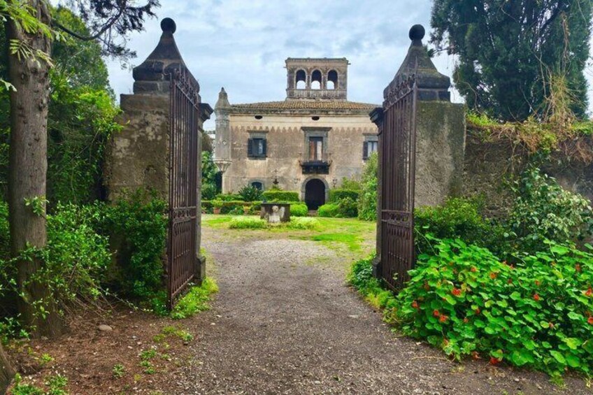 A historic building with a central archway, surrounded by lush greenery and a gravel path leading to it. 3