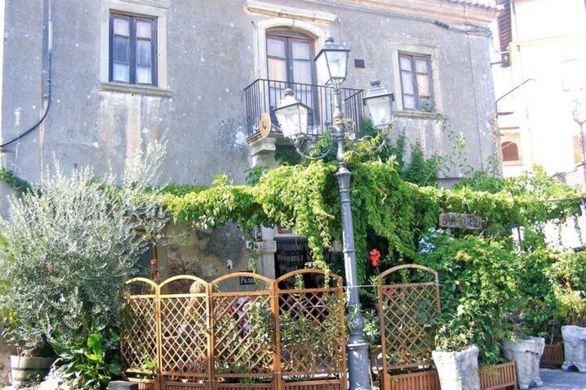 A building with a balcony, a street lamp, and a wooden fence with a sign. 2