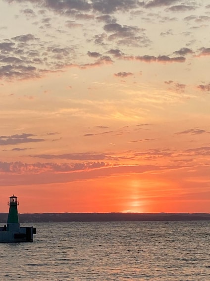 A sunset over a body of water with a lighthouse in the foreground. 3