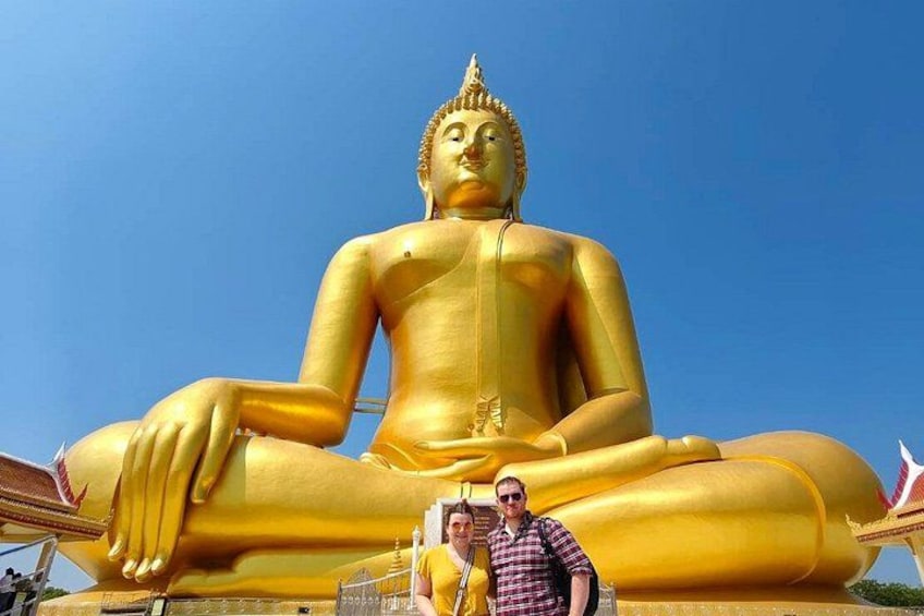 Una grande statua dorata di Buddha con una persona che si trova di fronte. 5