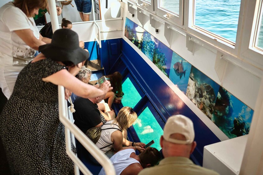 Passengers on a boat with an aquarium wall displaying marine life. 4