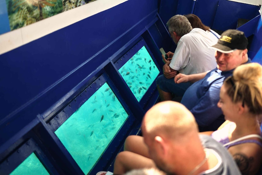 A group of people observing fish through a large aquarium window. 1