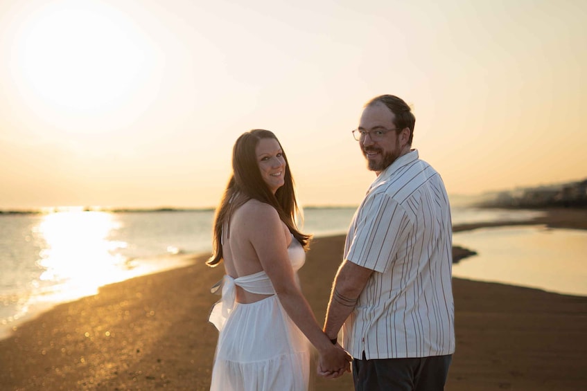 A couple holding hands on a beach at sunset. 2