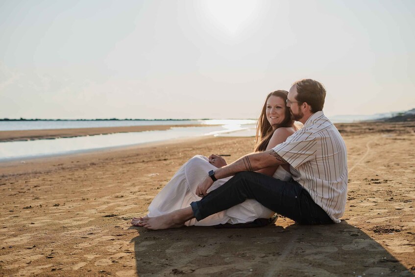 A couple sitting on a blanket on a sandy beach with the ocean in the background. 4
