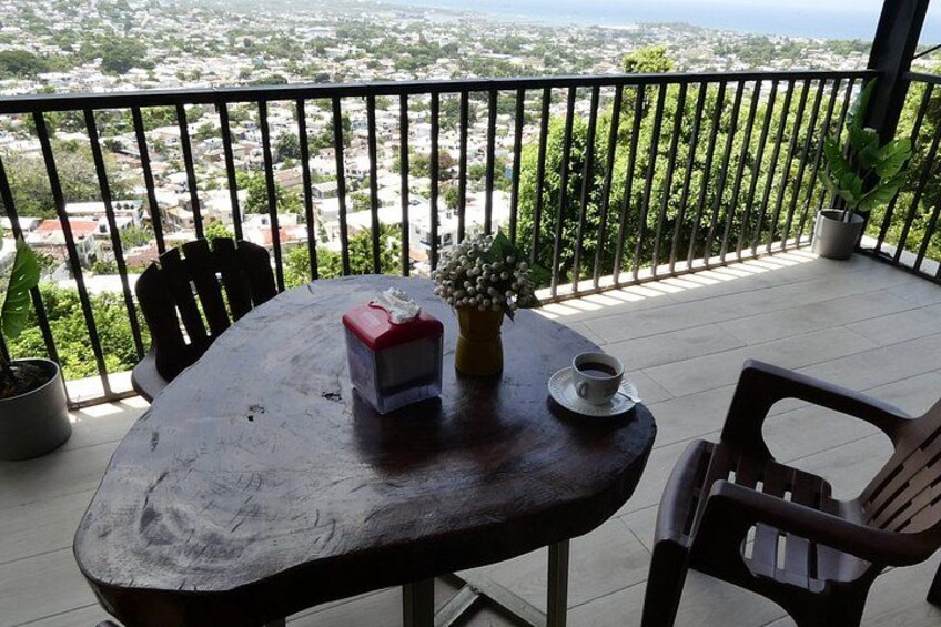 Een houten tafel met stoelen op een balkon met uitzicht op een stadsbeeld. 3