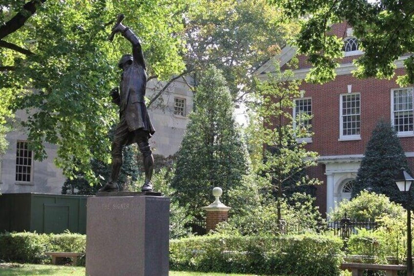Una estatua de un hombre en un parque, con un edificio al fondo. 2