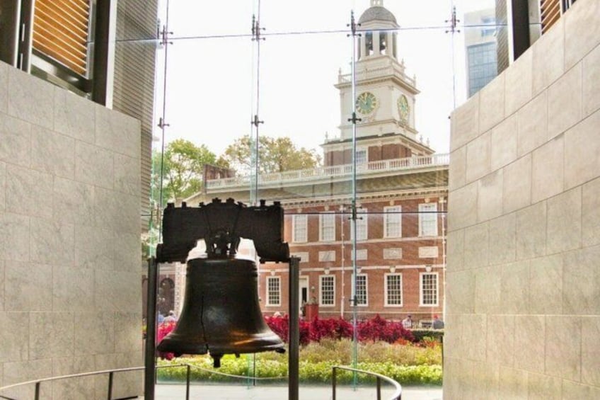 Una campana grande en una plaza, con una torre de reloj al fondo. 5
