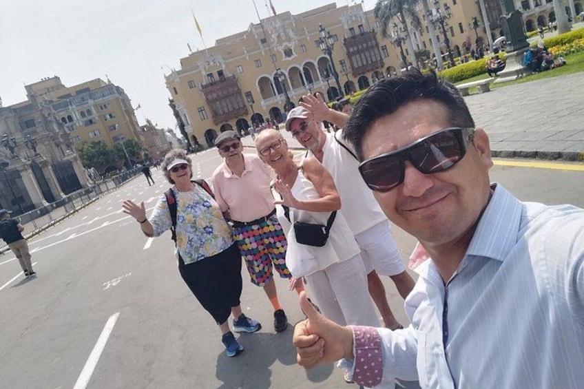 A group of people taking a selfie in a public square with historic buildings in the background. 1