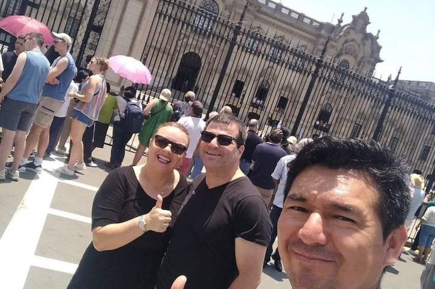 A group of people standing in front of a large, ornate building with a wrought iron fence. 4