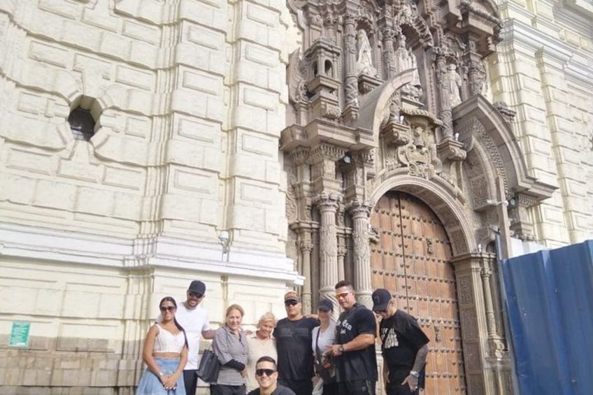 A group of people standing in front of a historic building with ornate architecture. 3