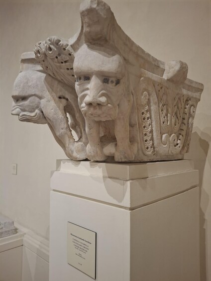 A marble sculpture with intricate carvings, mounted on a pedestal with a descriptive plaque. 2