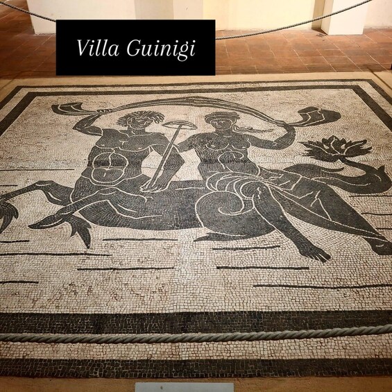 A mosaic floor with two figures, a rope, and a sign reading 'Villa Guinigi'. 3