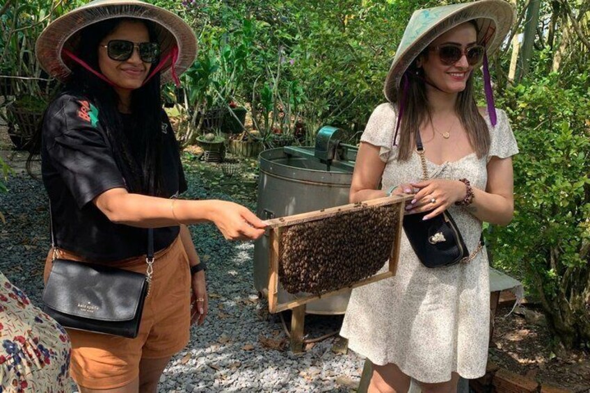Two individuals in a garden holding a beehive. 2