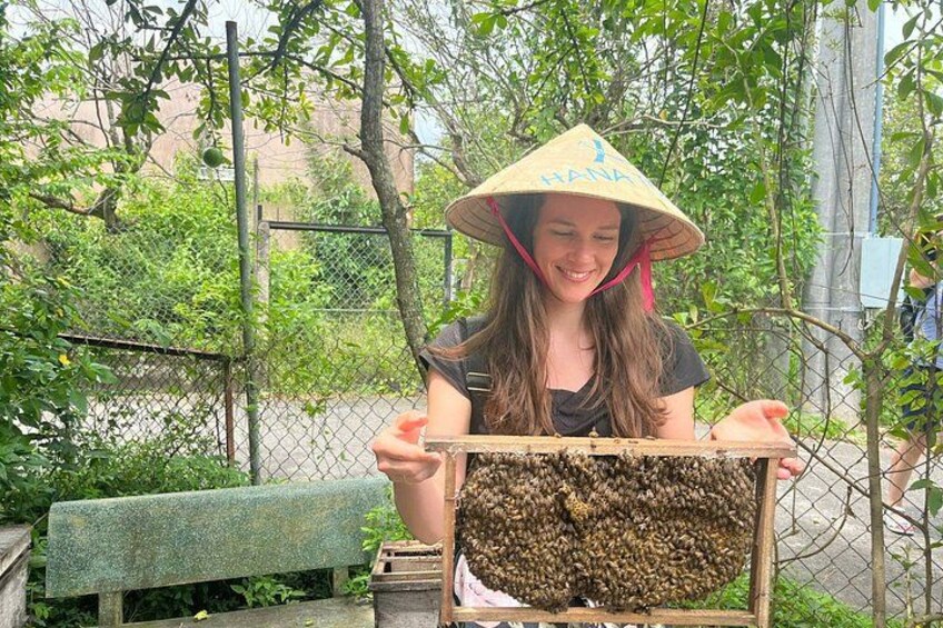 A person wearing a conical hat holding a beehive. 4