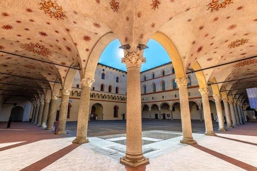 Un patio abierto con arcos, columnas y un edificio al fondo. 3