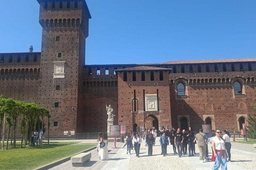 Un edificio histórico con una torre alta, ventanas arqueadas y una estatua en primer plano. 1