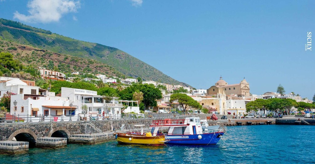 A coastal town with a church, a restaurant, and boats docked at the harbor. 3
