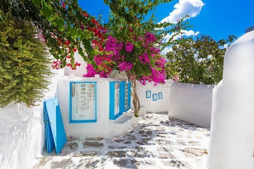 Un bâtiment aux murs blanchis à la chaux, agrémenté de touches de bleu, un arbre aux fleurs roses et un ciel d’un bleu limpide. 3