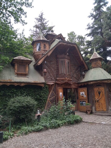 A wooden house with a steeply pitched roof, a small tower, and a door with a unique design. 2