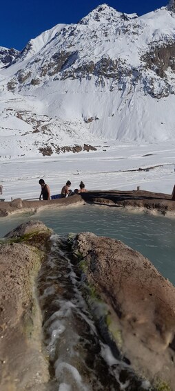 A mountainous landscape with snow-covered peaks and a geothermal area with hot springs. 3