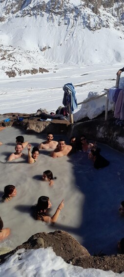 A group of people in a natural hot spring surrounded by snow-covered mountains. 5