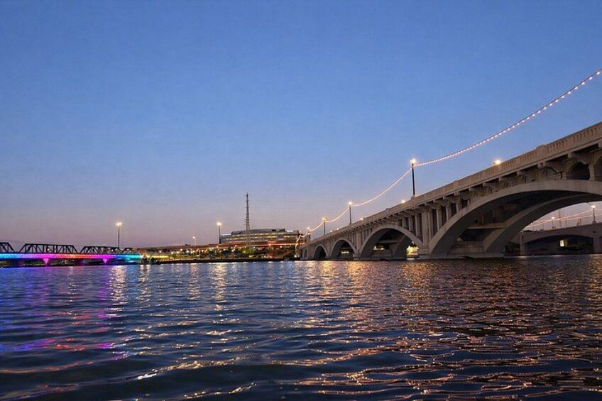 A bridge over water with lights and a distant building. 4