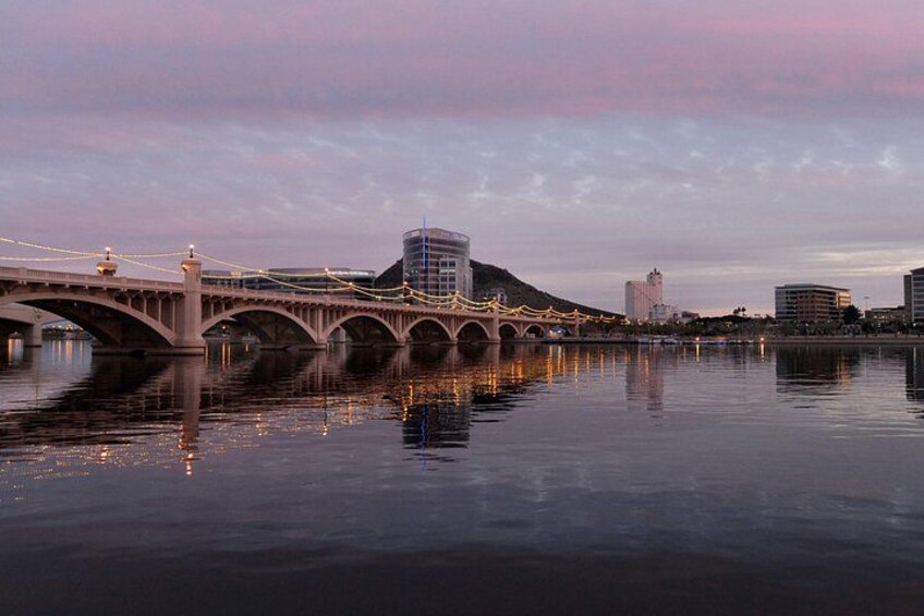 A bridge with multiple arches over a body of water, reflecting the sky and surrounding buildings. 3