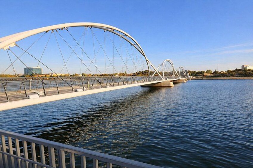 A white arched bridge over a body of water with a clear sky. 2