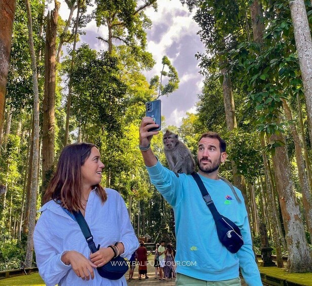 Kaksi ihmistä ottaa selfien, ja apina istuu miehen olkapäällä metsäisessä ympäristössä. 5