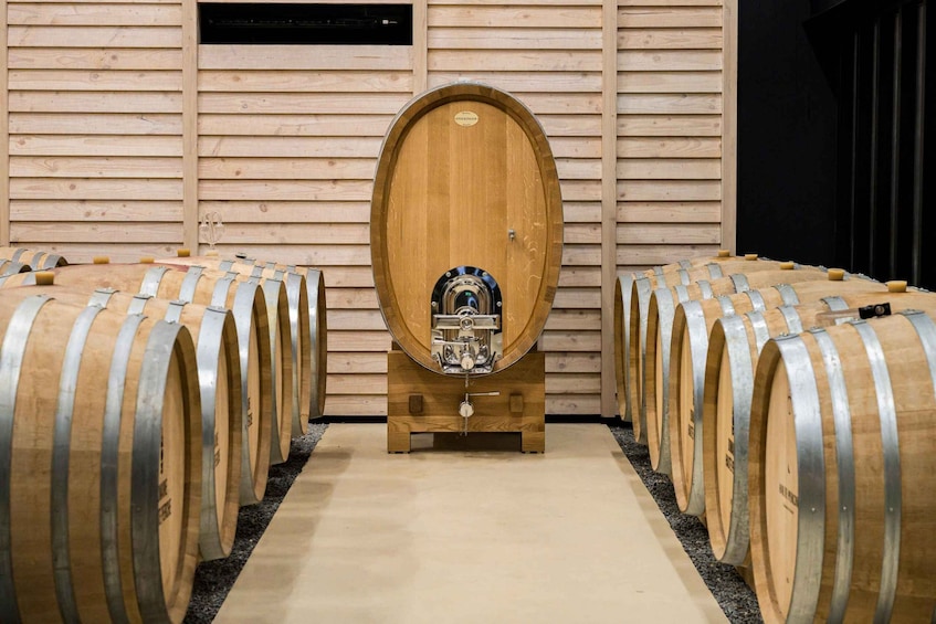A row of wooden barrels with a central barrel on a stand in a room with wooden walls. 1