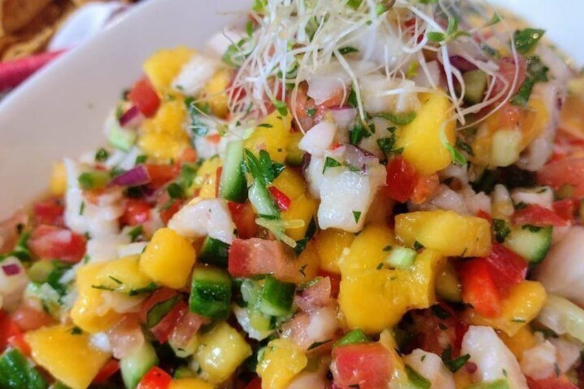 Een kleurrijke fruitsalade met stukjes mango, komkommer en rode tomaten, versierd met kiemgroenten. 1