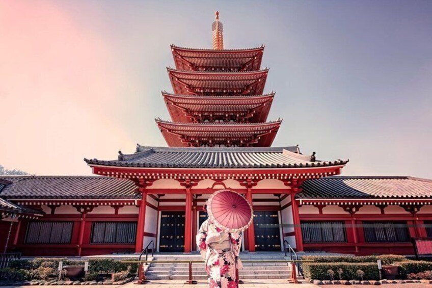 Una pagoda tradizionale a più livelli, con dettagli rossi e bianchi, immersa in un giardino curato. 1