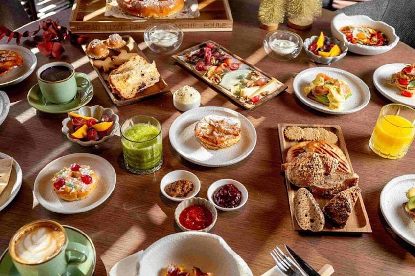 A variety of breakfast dishes on a wooden table, including pastries, bread, and fruit. 3