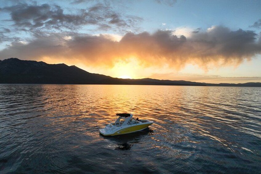 Een gele boot op rustig water tijdens de zonsondergang, met bergen op de achtergrond. 3