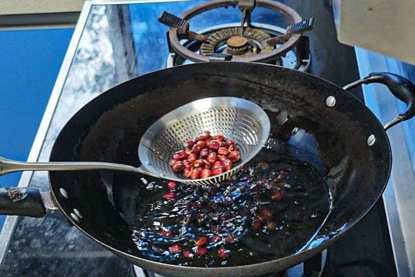 A frying pan with a metal strainer containing red beans over a stove. 4