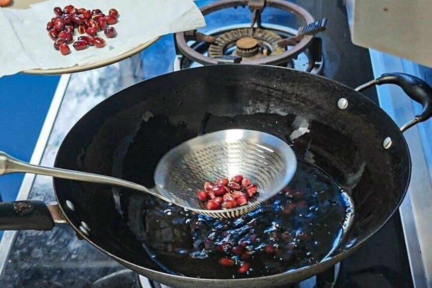A wok on a stove with a strainer containing red beans. 3
