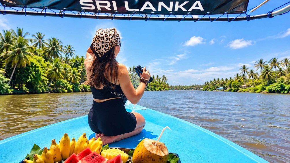 A person sitting on a boat with a tropical backdrop, a sign reading 'SRI LANKA', and various fruits on the deck. 3