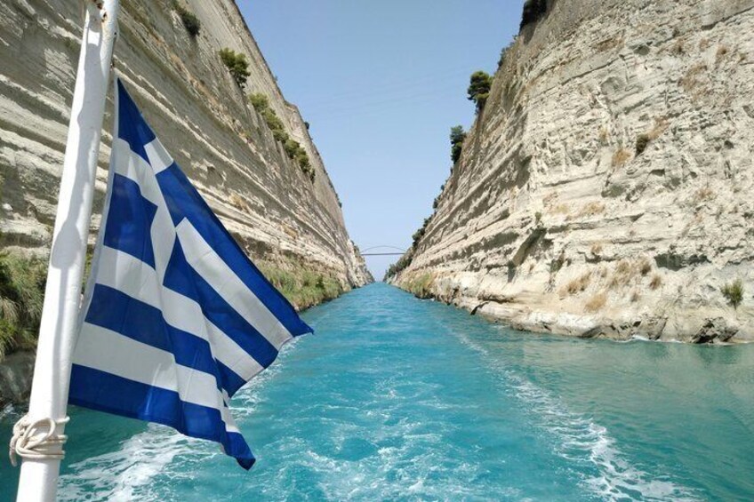 Un canal estrecho bordeado por acantilados empinados, una bandera y agua cristalina azul. 3