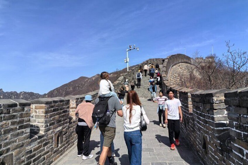 Un groupe de personnes se promène le long de la Grande Muraille de Chine, sous un ciel dégagé. 4