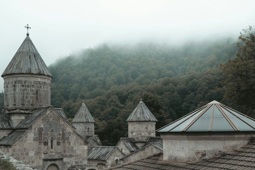 A historic church with multiple steeples and a forested hillside in the background. 2