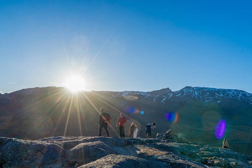 Een groep mensen op een berg, met de zon die op de achtergrond schijnt. 3