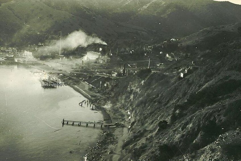 A mountainous landscape with a body of water, a dock, and industrial structures. 2